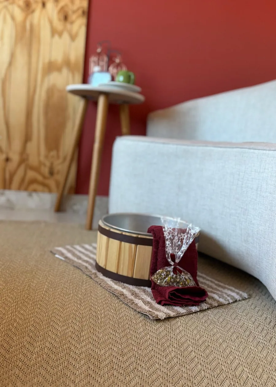 Poltrona clara e mesa lateral com vela em um consultório de parede terracota