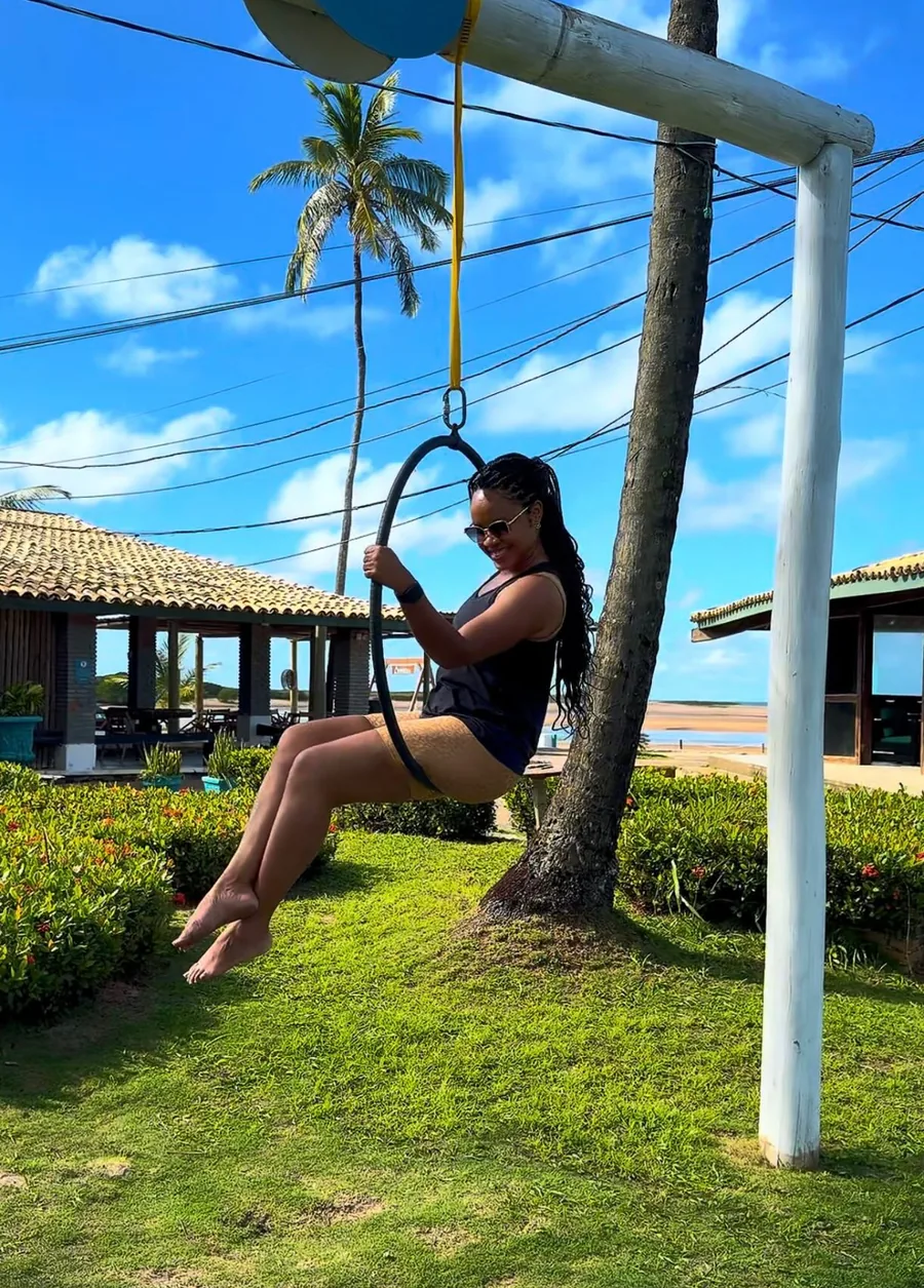 Dalila Garcez em um balanço à beira-mar, em um dia de sol
