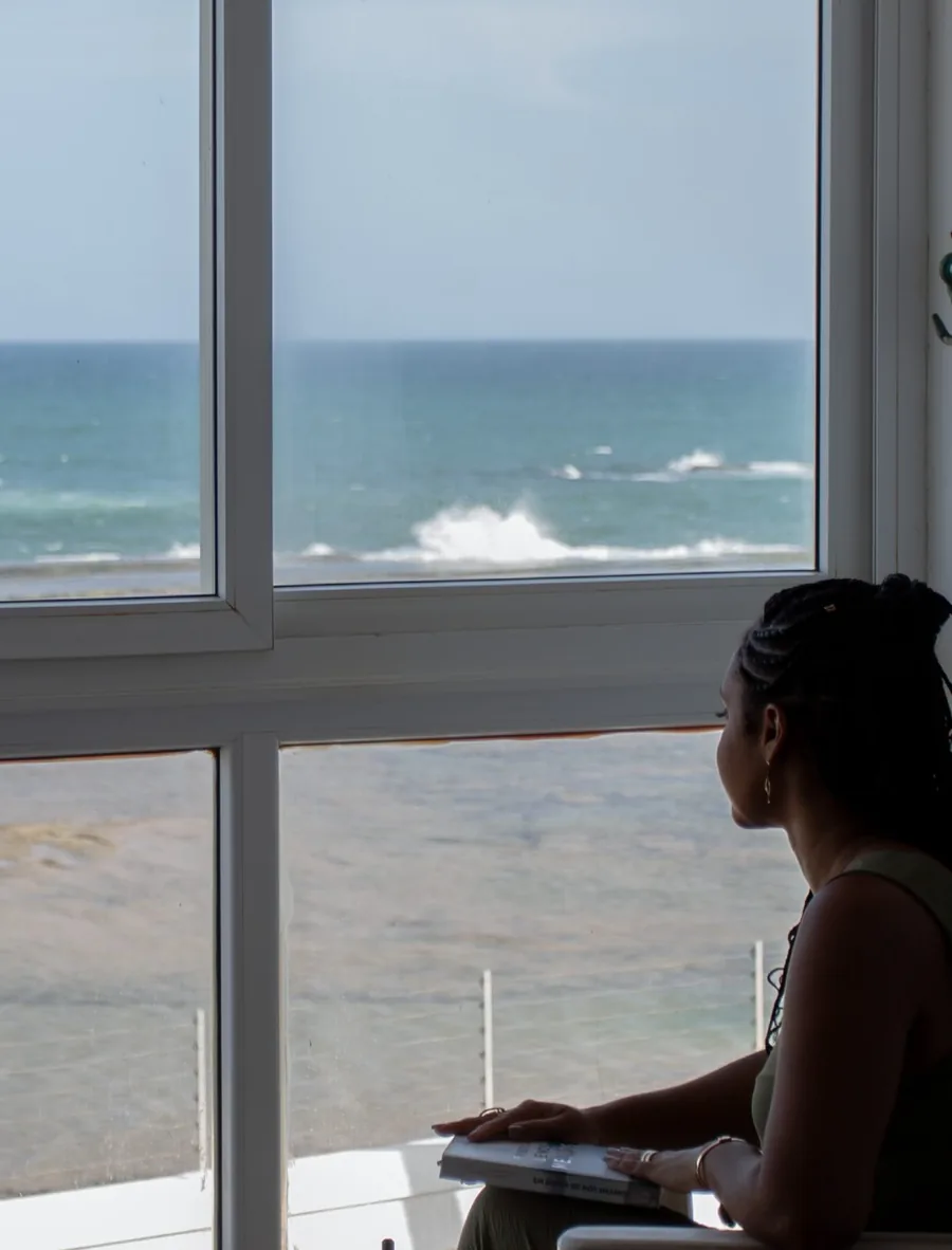 Dalila Garcez trabalhando diante de uma janela com vista para o mar